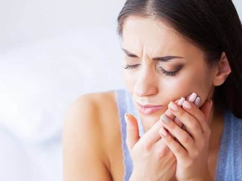 Patient holding a broken tooth while contacting an emergency dentist for prompt treatment after a weekend dental accident | Break a Tooth on the Weekend
